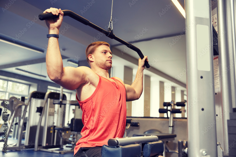 man flexing muscles on cable machine gym man flexing muscles on cable machine gym