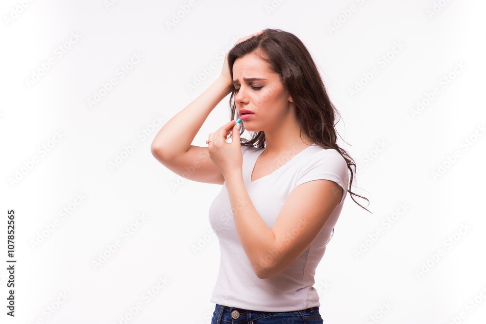 Young woman showing a pill with severe head pain and eat tablet on white Young woman showing a pill with severe head pain and eat tablet on white