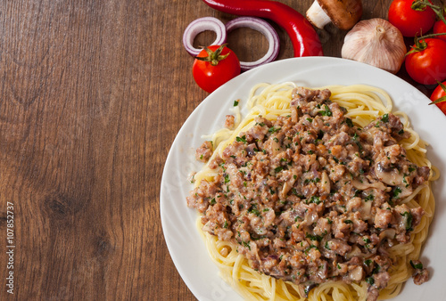 spaghetti with mushroom and minced meat in a plate on wooden table