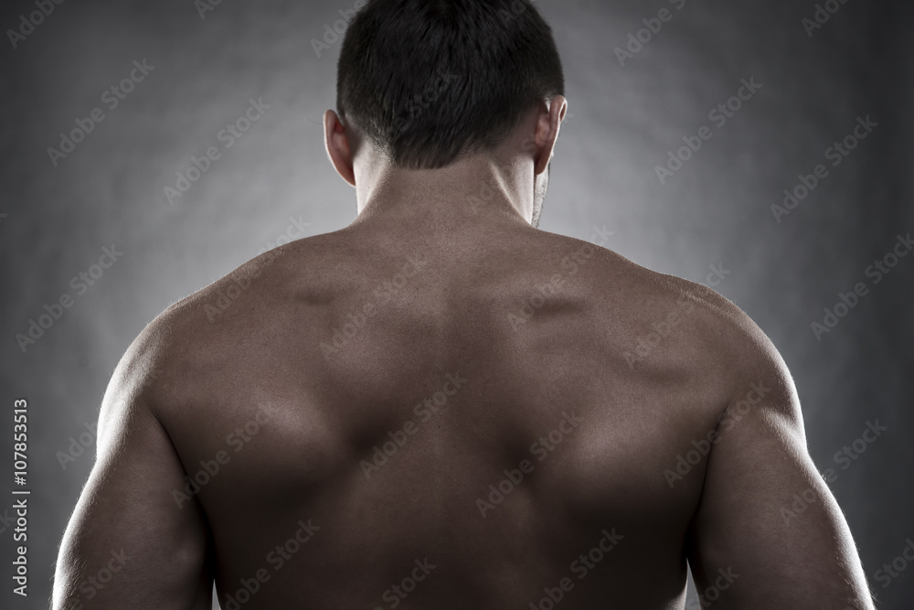 Handsome muscular bodybuilder posing on gray background. Low key studio shot Handsome muscular bodybuilder posing on gray background. Low key studio shot