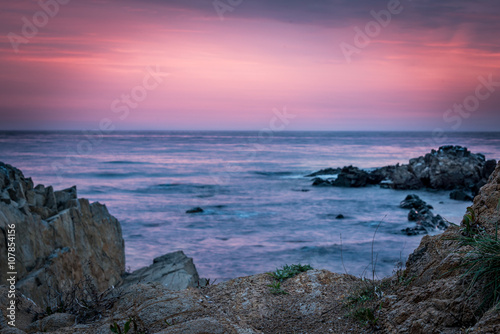 Colorful sunrise skyline viewed from the beach rocks