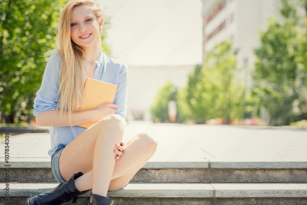 smiling blonde young woman with book relax in a garden