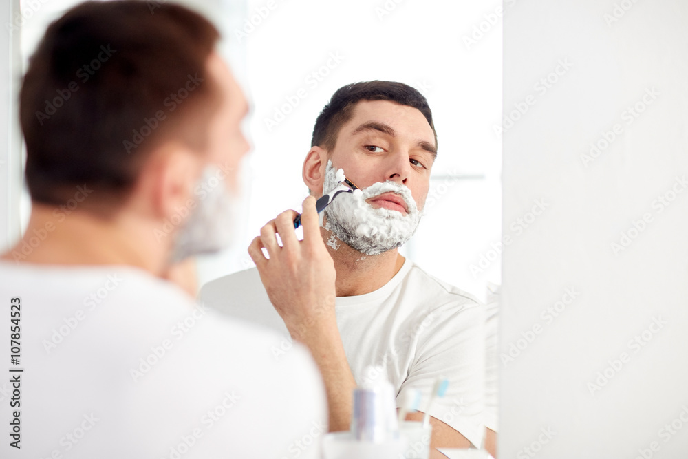 man shaving beard with razor blade at bathroom