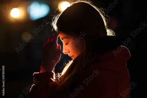 Closeup portrait of a young  woman praying