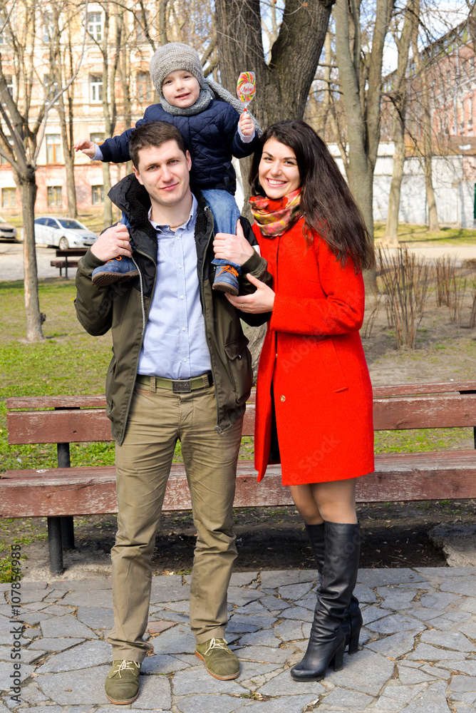 Porttrait of happy young family spending time together in green nature in park. European family having fun outdoors on a spring sunny day. Concept of happy family life, love and happiness. 