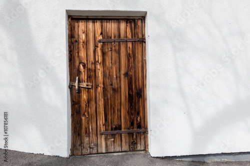 dunkle alte Holztür in einer weißen Hauswand photo