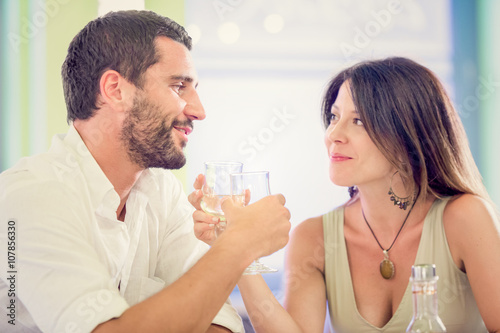 Young romantic couple drink to each other at restaurant