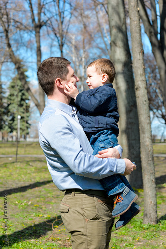 Father and son having fun outdoors on a spring sunny day. Happy smiling little boy in the arms of his dad. Concept of happy family life, love and happiness.  © ISOstudio