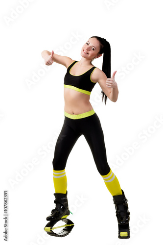 slender brunette girl in kangoo jumps shoes showing a fingers up, sign OK. Isolated on white background