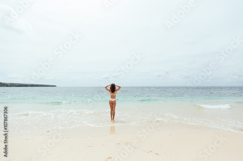 Beautiful girl in swimsuit walking along the beach.back view