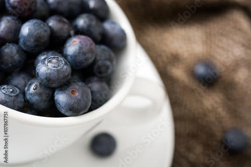 blueberries in a white cup on a brown cloth