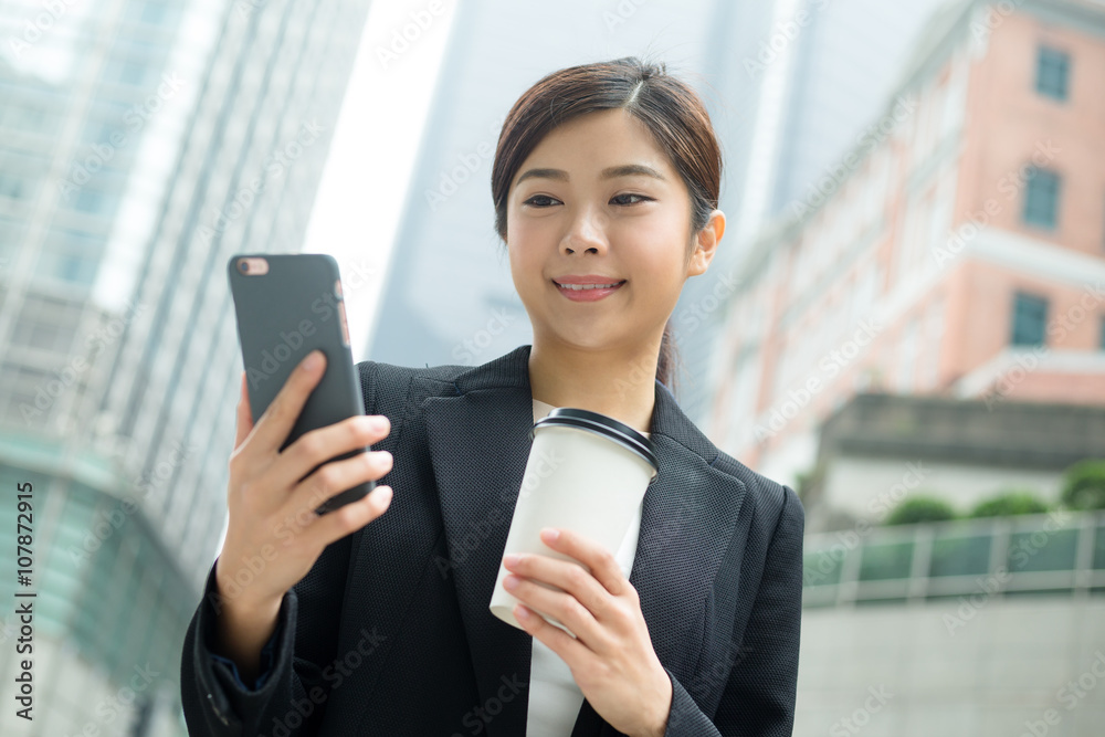 Business woman look at her cellphone and holding with coffee cup Business woman look at her cellphone and holding with coffee cup