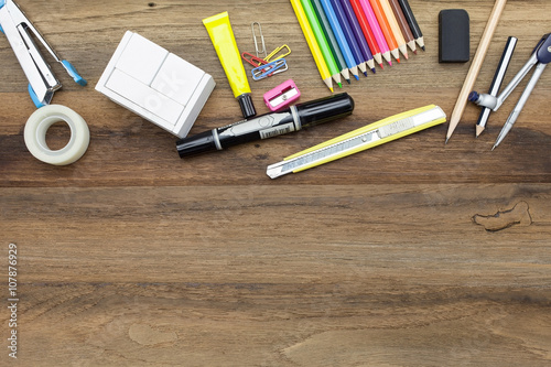 Business concept:stapler,color,pencil,divider,rubber,pencil,glue,sharpener,tape and pen on wooden plank background