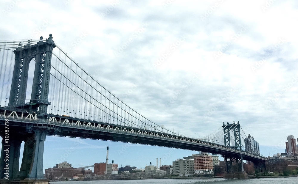 Manhattan bridge and the city under cloudy sky, New York