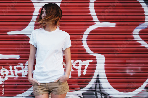 young attractive girl wearing a white t-shirt posing on a graffiti wall background