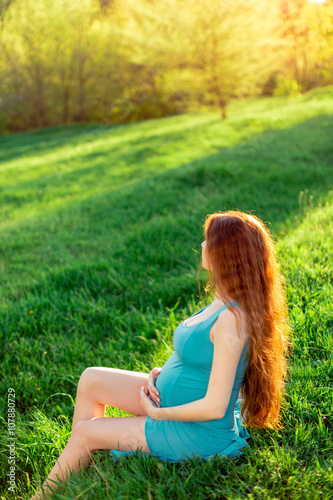 Beautiful pregnant woman in the garden. Sunset or sunrise