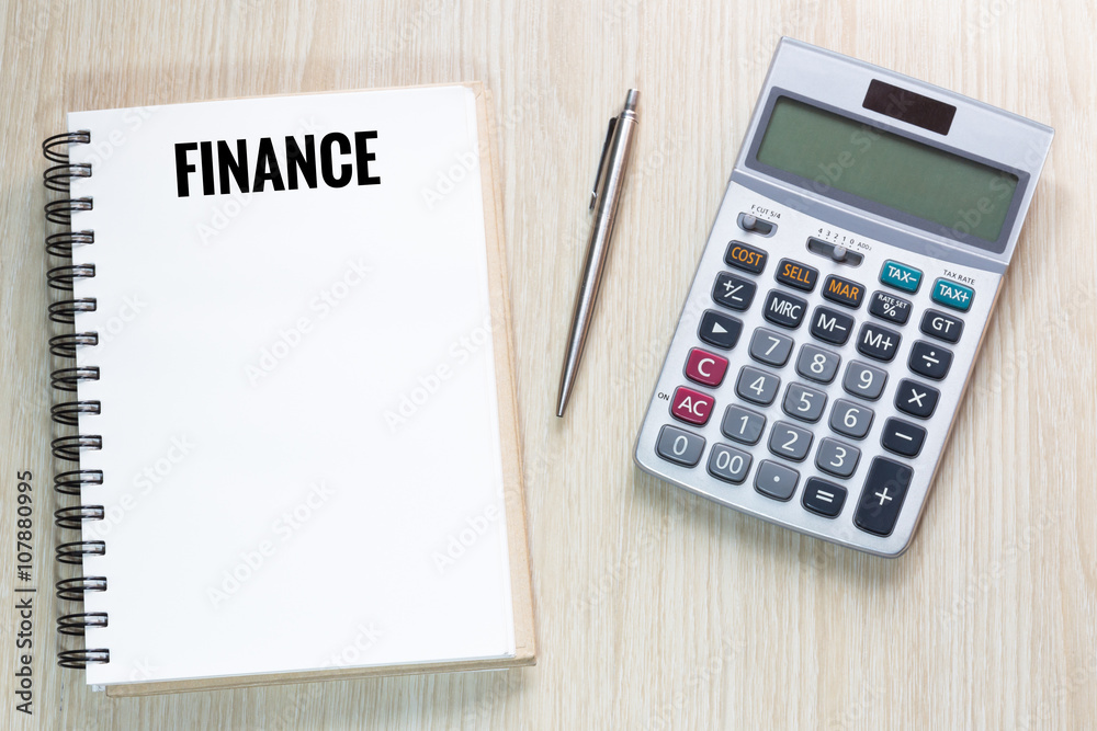 Top view of Finance wording on notebook with calculator and pen Top view of Finance wording on notebook with calculator and pen