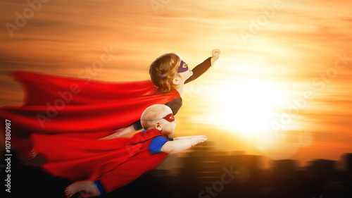 children superheroes flying across sunset sky