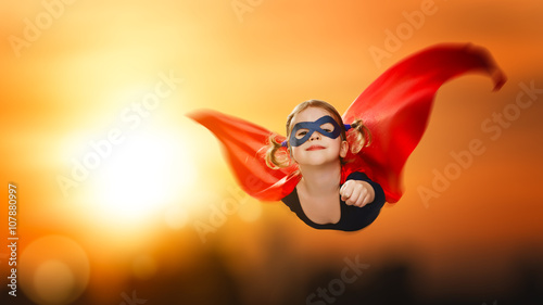 Foto child girl superhero flying through sky at sunset