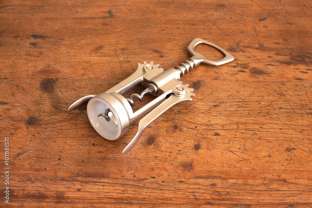 Gray corkscrew on wooden background closeup. Tool for pulling out wine corks Gray corkscrew on wooden background closeup. Tool for pulling out wine corks