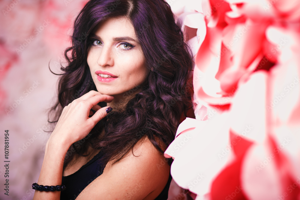 Portrait of beautiful brunette woman with perfect make up and hair style over background with flowers