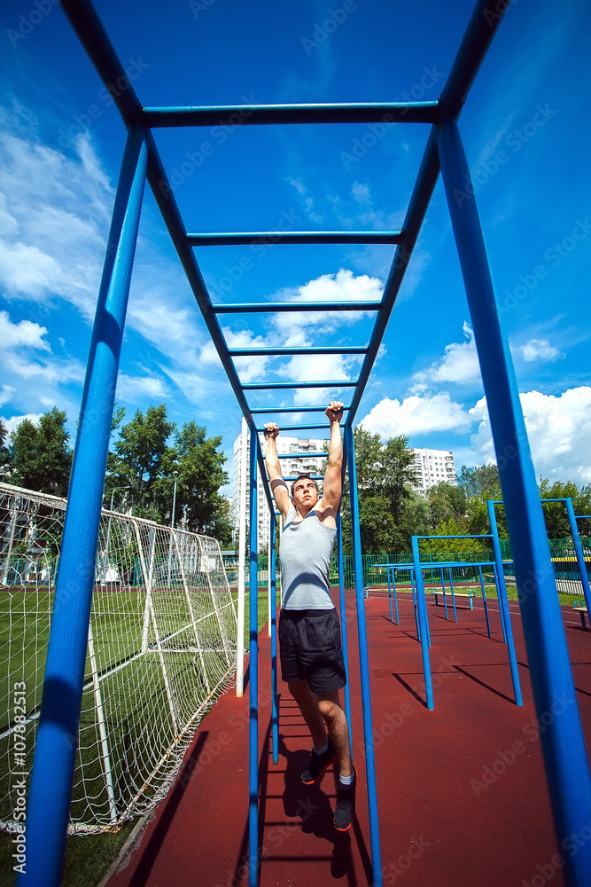 Muscular man doing pull-ups on horizontal bar Muscular man doing pull-ups on horizontal bar