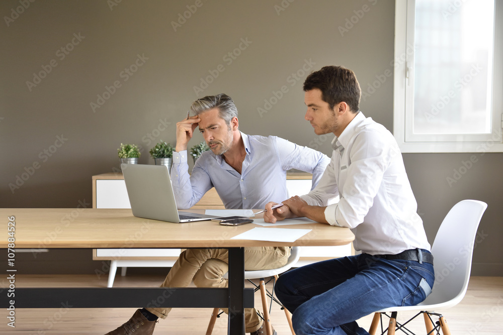 Businessmen working together in office with laptop Businessmen working together in office with laptop