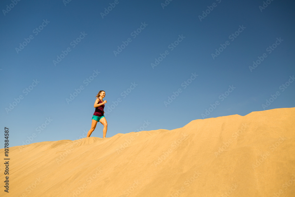 Young woman running on sand desert dunes Young woman running on sand desert dunes