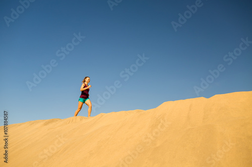Young woman running on sand desert dunes