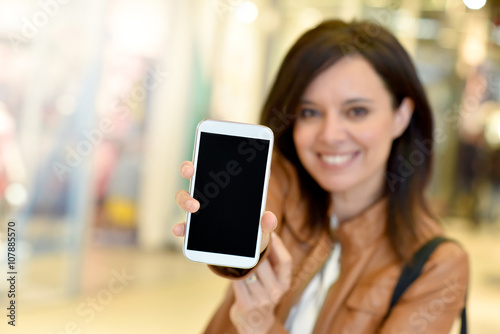 Woman in shopping mall showing smartphone