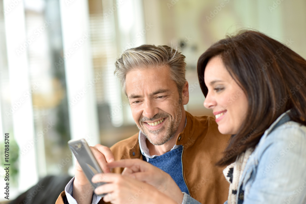 Mature couple using smartphone in coffee shop Mature couple using smartphone in coffee shop