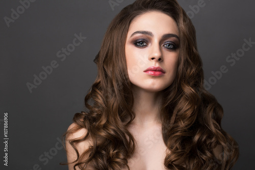 Fashion portrait of young woman with magnificent curly hair. Bru