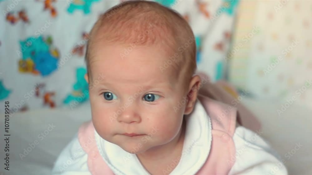 A cute little baby looking into the camera. The child looks around. A cute little baby looking into the camera. The child looks around.
