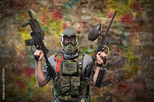 Handsome paintball gamer with guns
