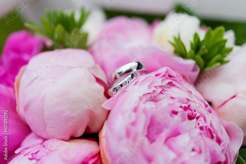 Fototapeta Naklejka Na Ścianę i Meble -  Golden wedding rings with diamonds lie inside peony flower in bridal bouquet. Symbol of love and marriage. 