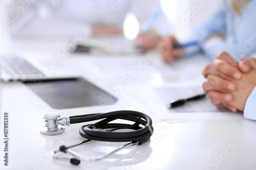 Medical doctor and young couple patients discussing something at the table . Hands close-up