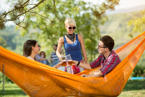 Couple in hammock in nature toast with glasses of beer with fema