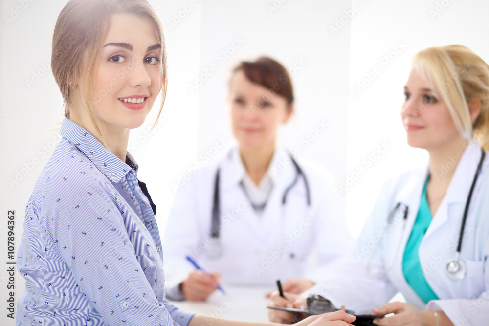 Happy smiling female patient with two cheerful doctors in the background. Medical and health care concept Happy smiling female patient with two cheerful doctors in the background. Medical and health care concept