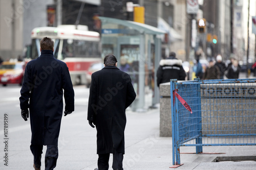 Canvas Print two men walking next to a barricade