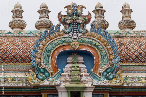 Trichy, India - October 15, 2013: Closeup of bow decoration on the Vimanam of one Gopuram at Shirangam temple. Monster face on top of bow with bulk of brown-beige vimanam as background.