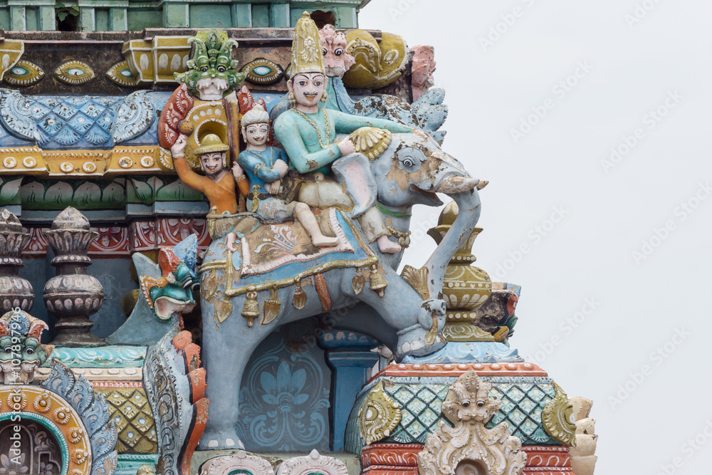 Trichy, India - October 15, 2013: Closeup of  decoration on one Gopuram at Shirangam temple. Three people riding an elephant. One royal. Pastel colors, gray sky.
