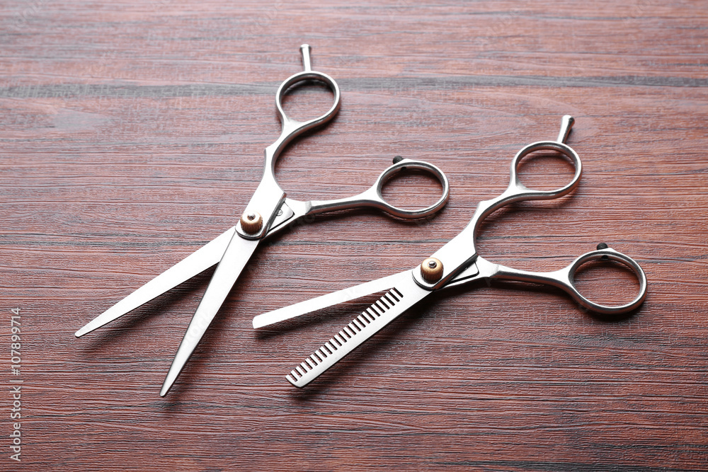 Two professional metal scissors lying on the wooden table, top view Two professional metal scissors lying on the wooden table, top view