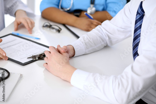 Two doctors and male patient discussing medical history at the table, close up