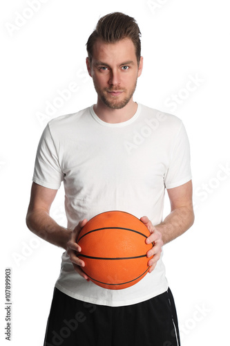 Focused basketball player wearing a white tshirt and holding a basketball. Standing against a white background staring at camera. © _robbie_