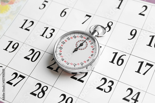 Stopwatch on calendar background, close up