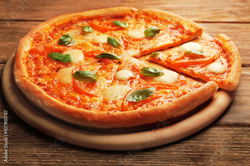 Sliced Margherita pizza on wooden background
