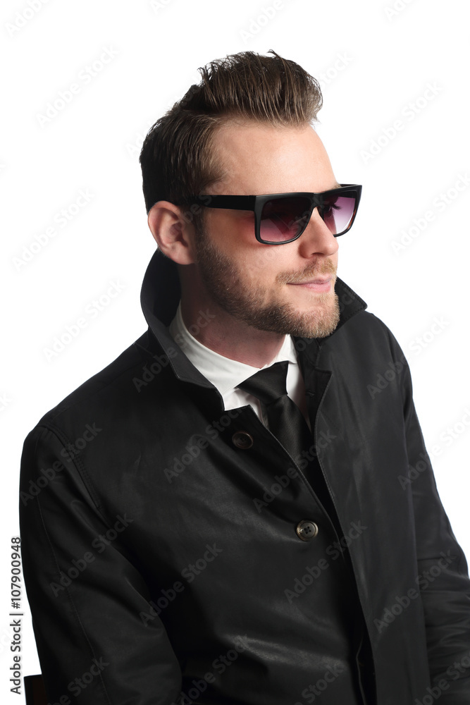 Portrait of an attractive and trendy man sitting down with a white background, wearing a black jacket, white shirt, black tie and dark sunglasses. Looking away from camera. Portrait of an attractive and trendy man sitting down with a white background, wearing a black jacket, white shirt, black tie and dark sunglasses. Looking away from camera.