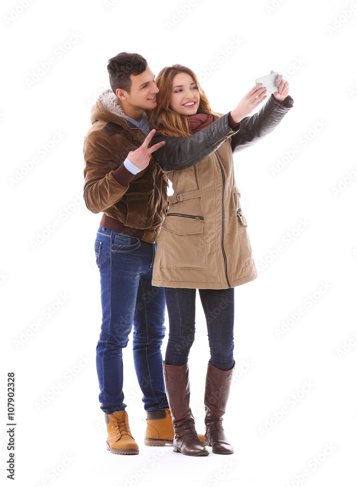 Young couple taking selfie in their winter clothes isolated on white Young couple taking selfie in their winter clothes isolated on white