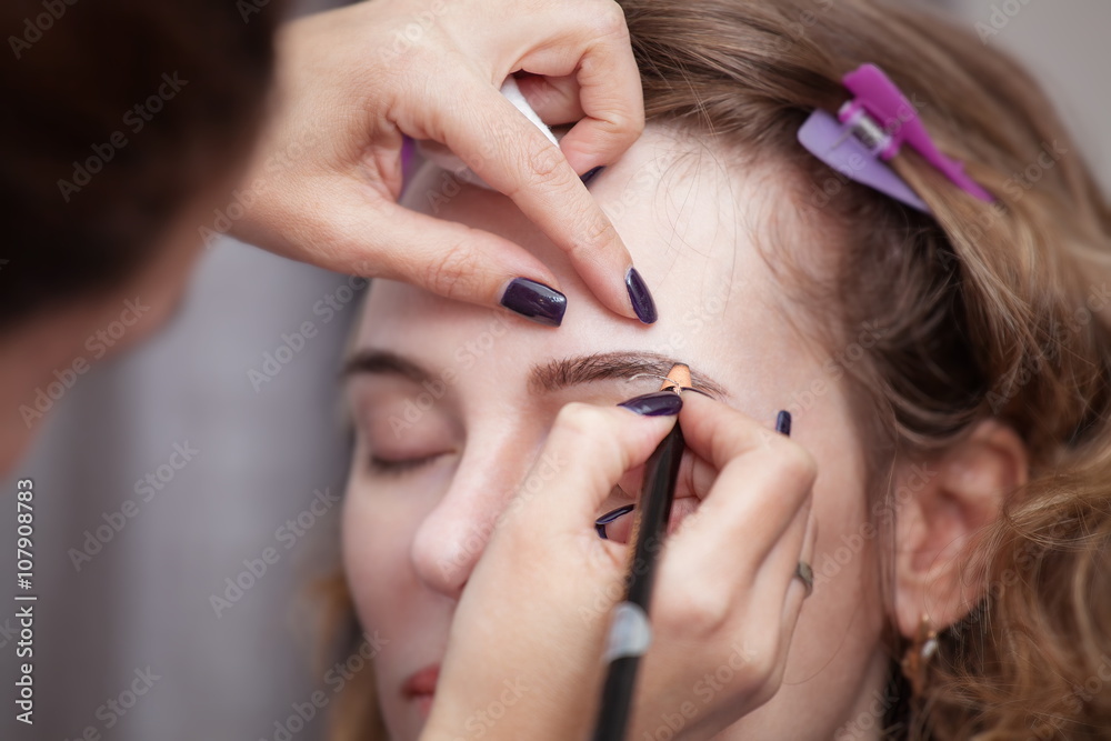 Cosmetologist applying permanent make up (tattoo) on eyebrows. Cosmetologist applying permanent make up (tattoo) on eyebrows.