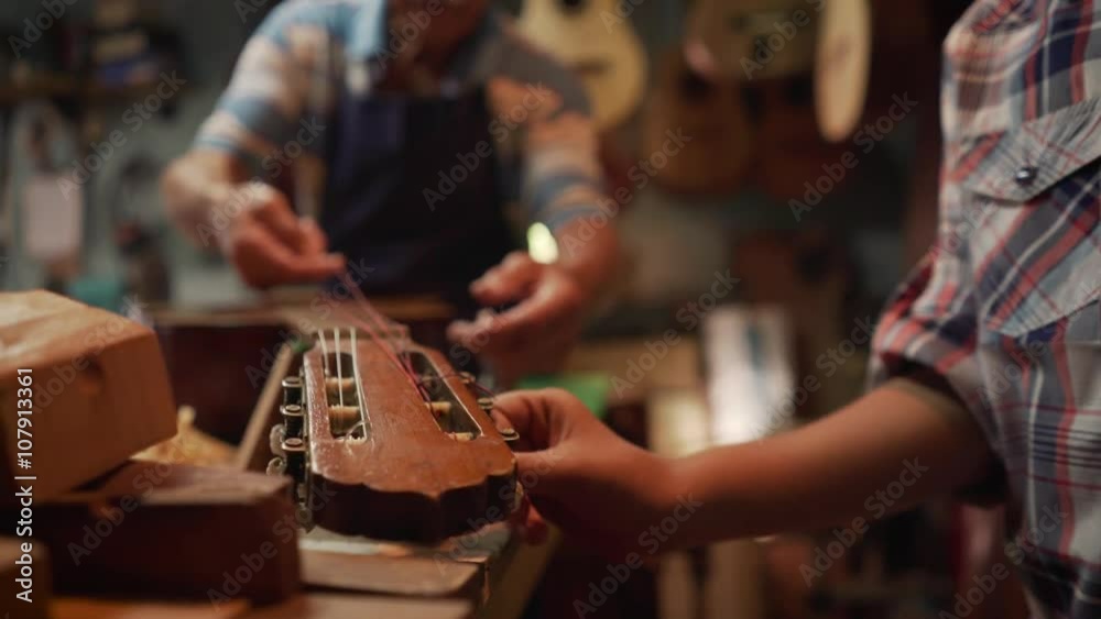 Old and young people showing love for music. Boy and senior man, happy kid and elderly person, grandfather showing guitars and instruments to grandson in lute maker shop. Proud retired worker